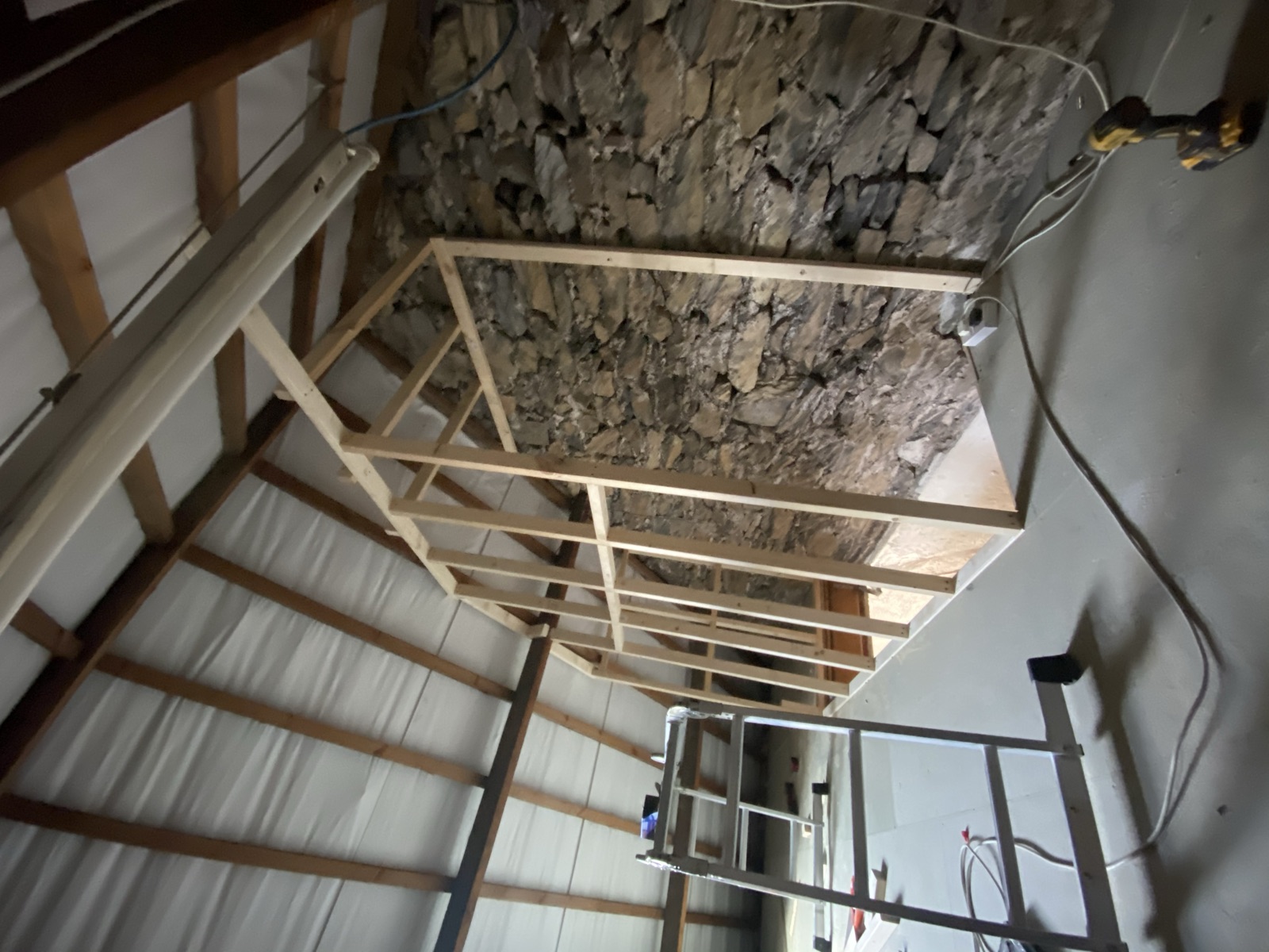 Timber studwork beside an existing stone wall